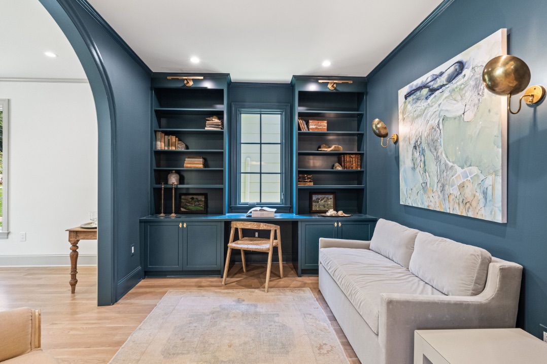 A thoughtfully detailed study with arched doorway, built in cabinetry and brass sconces